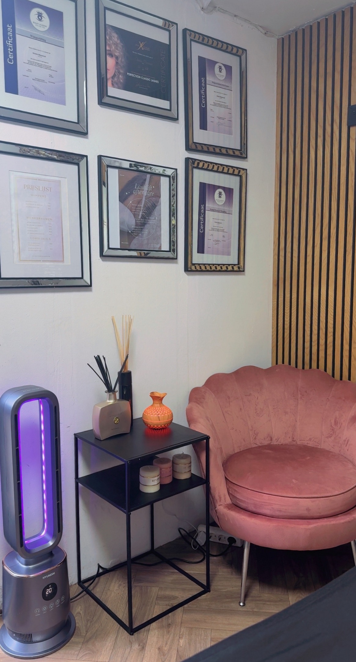 Roze salonstoel naast een wand met certificaten